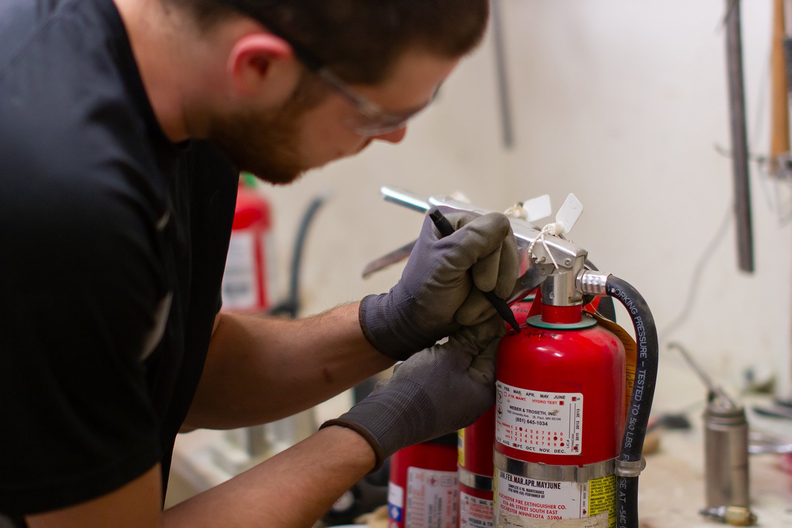Technician labeling an extinguisher for recharge service needed for fire equipment