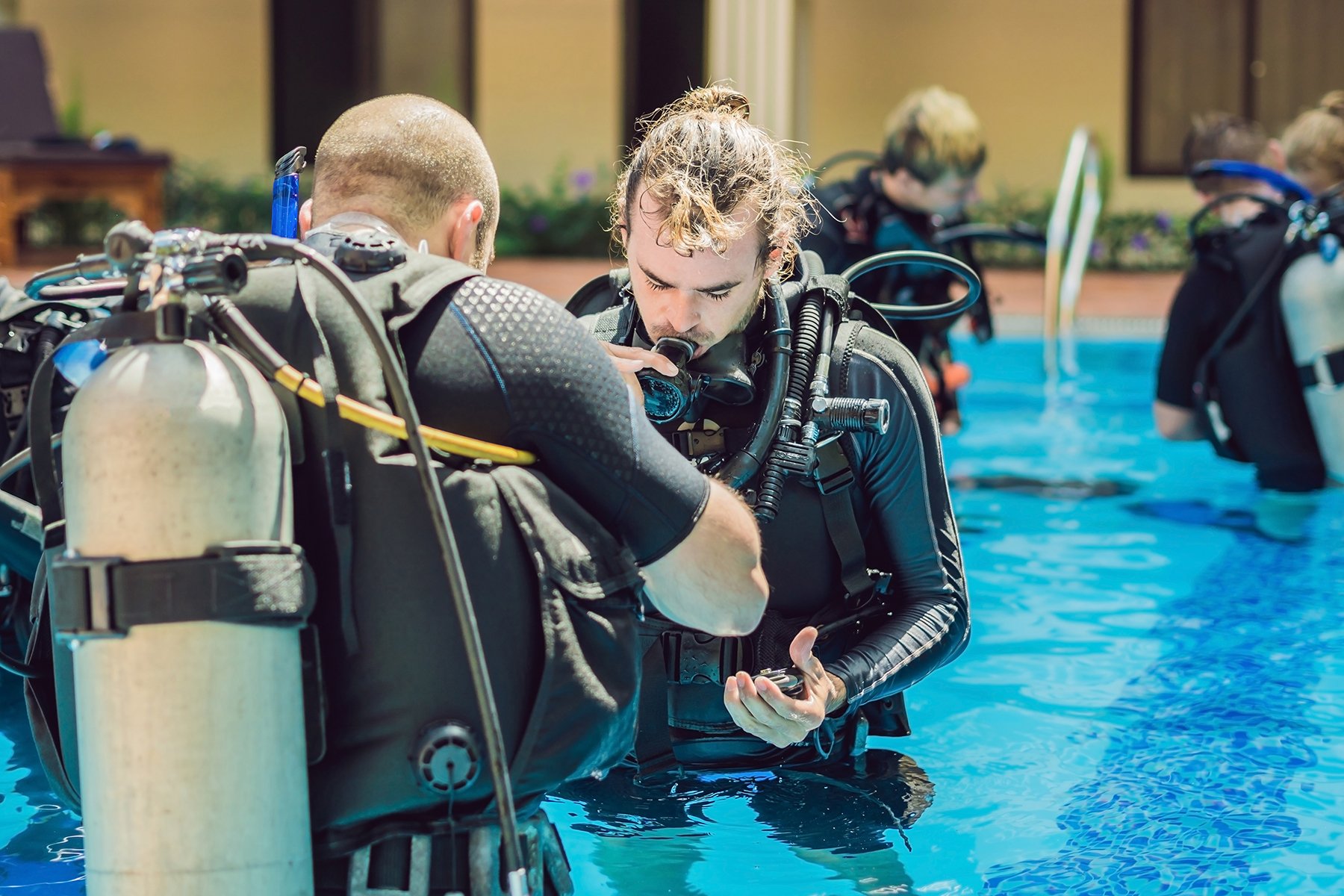 Scuba instructor showing how to use high pressure air tanks for breathing
