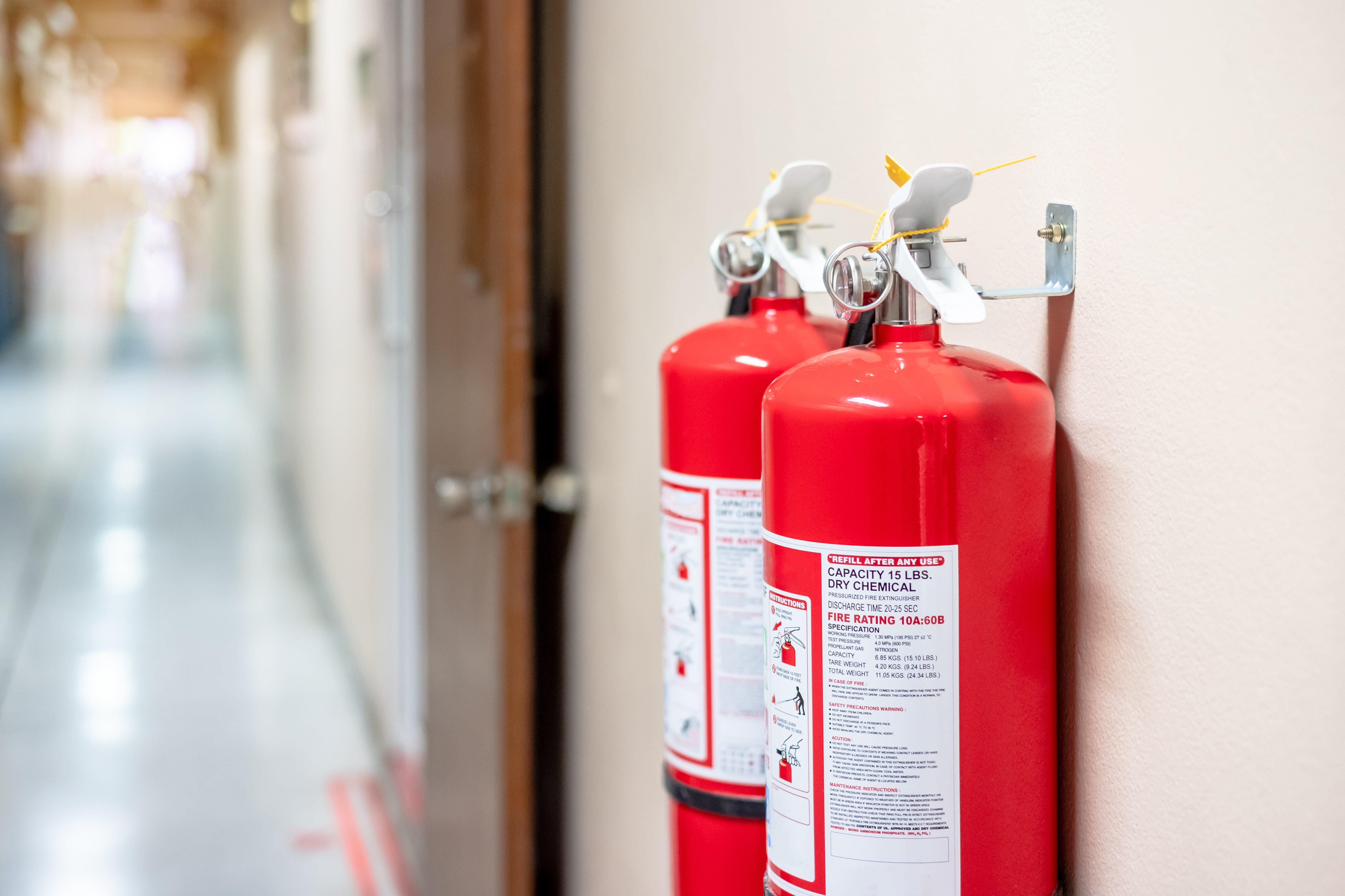 Fire extinguishers mounted to a wall in a building that need annual inspections